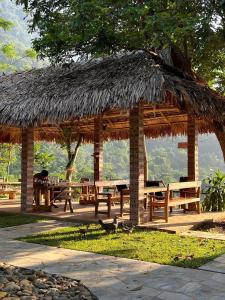 a wooden pavilion with benches and a grass roof at Pu Luong - Duy Phuong Homestay in Thanh Hóa
