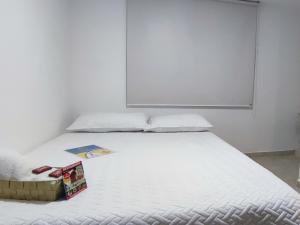 Una cama blanca con un libro encima. en HOTEL CUMANDAY, en Pereira