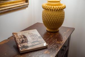 um vaso sentado numa mesa ao lado de um livro em A Casa del Gioielliere em Palermo