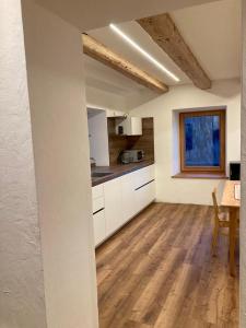 a kitchen with white cabinets and a wooden floor at Cèsa Sès da mont in Livinallongo del Col di Lana