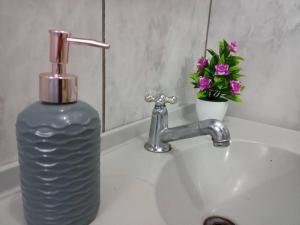 eine Flasche Wasser auf einem Waschbecken neben einem Wasserhahn in der Unterkunft Apto Confortável e espaçoso 01 in Cachoeira do Sul