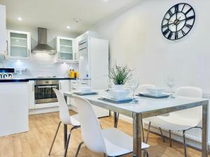 a kitchen with a table and chairs and a clock on the wall at Sutton - Ground Floor Flat By The High Street in Sutton