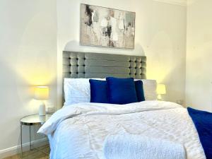a bedroom with a large bed with blue pillows at Sutton - Ground Floor Flat By The High Street in Sutton