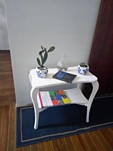 una mesa lateral blanca con un libro y una planta en Tu casa en Montevideo, en Montevideo