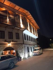 two cars parked outside of a building at night at Hotel Demaj in Berat