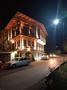 een gebouw waar 's nachts auto's voor geparkeerd staan bij Hotel Demaj in Berat