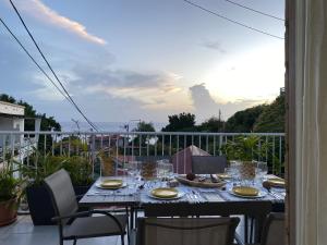 een tafel met glazen en borden op een balkon bij Mémoires des Flots Vue Mer, Jacuzzi, Ville à Pieds in Basse-Terre