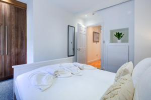 a bedroom with a white bed with towels on it at Spacious One Bedroom Apartment in The Heart Of Brentwood in Brentwood
