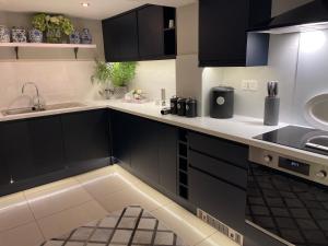 a kitchen with black cabinets and a sink at Cosy Cottage - Church St, Bawtry - Entire Cottage in Bawtry