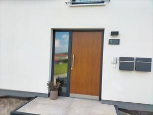 drewniane drzwi na białym budynku z doniczką w obiekcie Ferienwohnung Rote Leite w mieście Ebensfeld