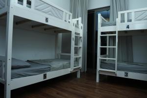2 letti a castello bianchi in una camera con pavimenti in legno di Shams JBR Hostel a Dubai