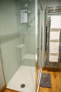 a shower with a glass door in a bathroom at 2 Bedroom Charming & Luxury Malt Cottage, Garden, Netflix, Free Parking in Bourton on the Water +17 photos