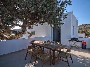 a wooden table and chairs on a patio with a tree at Private Luxury Scarlet beachfront villa, Molos, Paros in Molos Parou