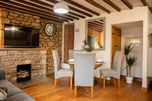 a living room with a table and chairs and a fireplace at 2 Bedroom Charming & Luxury Malt Cottage, Garden, Netflix, Free Parking in Bourton on the Water