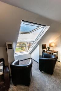 een zolderkamer met 2 stoelen en een groot raam bij Loft apartment in Accrington Stunning Lancashire views in Church