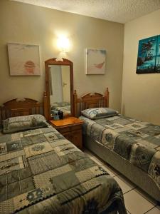 a hotel room with two beds and a mirror at Stella Maris 118 in Amanzimtoti +20 photos