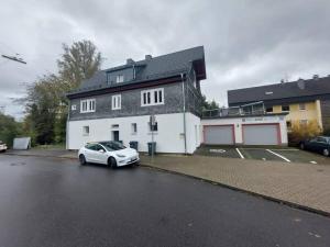 un coche blanco estacionado frente a una casa en Kinderklinik Dachwohnung Lion's Head 1B en Siegen
