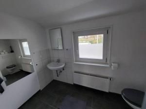 baño blanco con lavabo y ventana en Kinderklinik Dachwohnung Lion's Head 1B, en Siegen