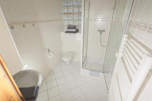 La salle de bains blanche est pourvue d'une douche et de toilettes. dans l'établissement Hotel Linde, à Speyer