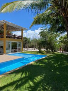 een zwembad voor een huis met een palmboom bij Quintas de Sauipe - modernes Haus im Condomínio mit Service in Mata de Sao Joao