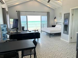 a bedroom with a bed and a desk and a television at Villas Secreta Beachfront Resort in San Pedro
