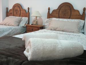 a bedroom with two beds and a table with a lamp at La Casa de la Plaza in Güéjar-Sierra