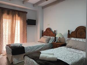 a bedroom with two beds and a tv on the wall at La Casa de la Plaza in Güéjar-Sierra
