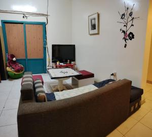 a living room with a couch and a tv at Bzxmax Guest House in Al Ain