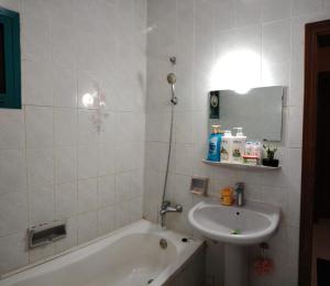 y baño con lavamanos, bañera y lavamanos. en Bzxmax Guest House, en Al Ain