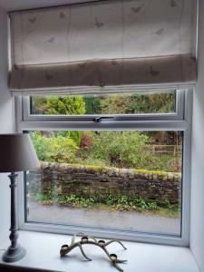 a window with a shade on a table with a lamp at Brook Terrace in Luddenden Foot