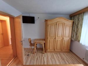Habitación con armario de madera, mesa y puerta. en Apartment Marina en Wenns