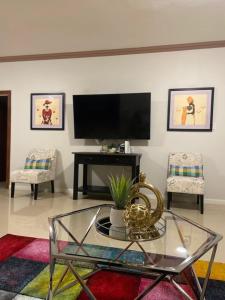 a living room with a tv and a glass table at Victory Luxury Apartments in Montego Bay