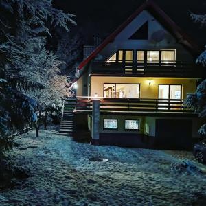 a house is lit up at night in the snow at Willa Bliski in Szczyrk