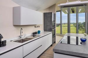 une cuisine avec des placards blancs et une grande fenêtre dans l'établissement Luxury Converted Water Tower In Yorkshire, à Emley