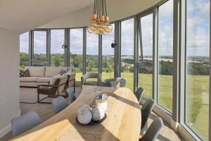 - une salle à manger avec une table, des chaises et des fenêtres en verre dans l'établissement Luxury Converted Water Tower In Yorkshire, à Emley