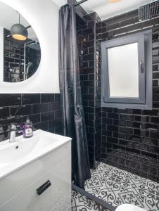 a bathroom with black tiles and a sink and a mirror at Bonita Casa CUCA in Marbella