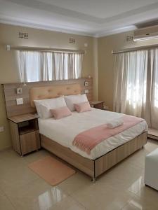 ein Schlafzimmer mit einem großen Bett mit rosa Kissen in der Unterkunft Casa MaSa Inn in Francistown