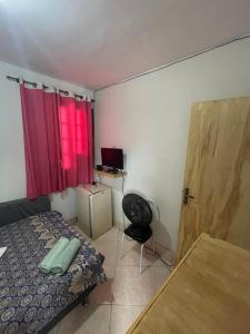 1 dormitorio con cama, escritorio y silla en Renan suítes, en Arraial do Cabo