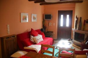 ein Wohnzimmer mit einem roten Sofa und einem Tisch in der Unterkunft Cozy Mountain Cabin in Karpenisi