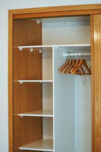 ein Schrank mit weißen Regalen und Holzschränken in der Unterkunft Apartamento Cristina - Próximo da praia in Armação de Pêra