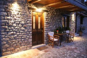 ein Steingebäude mit einer Holztür und einem Tisch in der Unterkunft Cozy Mountain Cabin in Karpenisi