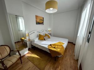 una camera da letto con un letto bianco con cuscini gialli di El paraíso de Lita - a 10 min del centro con WiFi a Oviedo