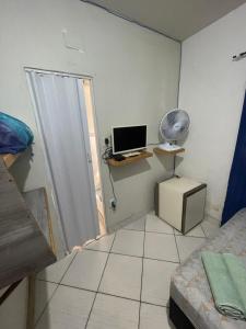 Habitación con cama y escritorio con ventilador. en Renan suítes, en Arraial do Cabo
