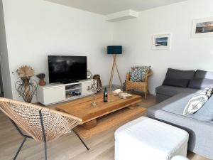- un salon avec un canapé et une télévision dans l'établissement Maison neuve 4 étoiles plain-pied proche de la mer, à Plurien