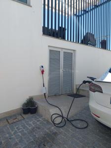 a car is parked next to a wall with a hose at Santiago 2 in Castelo do Neiva