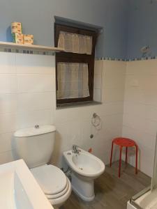La salle de bains est pourvue de toilettes, d'un lavabo et d'un tabouret rouge. dans l'établissement CASA STESICORO, à Catane
