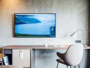 a desk with a chair and a television on a wall at Hotel Føroyar in Tórshavn