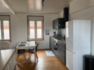 a kitchen with a table and a white refrigerator at Appartement Leforest Centre 50m2 in Leforest