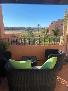 een balkon met 2 stoelen en een tafel met groene kussens bij Casa Paradise, Apartment in Torre-Pacheco