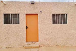 eine orangefarbene Tür an der Seite eines Gebäudes in der Unterkunft El Rincón de Petunio in Sayula